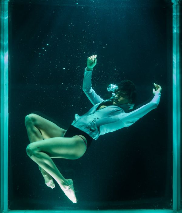 Woman in a graceful yoga pose with deep blue and honey yellow light accents.